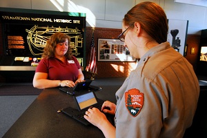 A uniformed park ranger use a Ubi Duo device to assist a visitor at the Visitor Center kiosk. A uniformed park ranger use a Ubi Duo device to assist a visitor at the Visitor Center kiosk.
