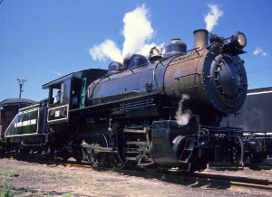 A small, black steam locomotive and tender, with a blue sky and white clouds in background at Steamtown NHS A small, black steam locomotive and tender, with a blue sky and white clouds in background at Steamtown NHS