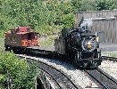 Steam locomotive pulls a flatcar and caboose. Steam locomotive pulls a flatcar and caboose.