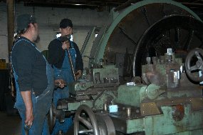 Two of Steamtown's mechanics trim railroad wheels on a large lathe. Two of Steamtown's mechanics trim railroad wheels on a large lathe.