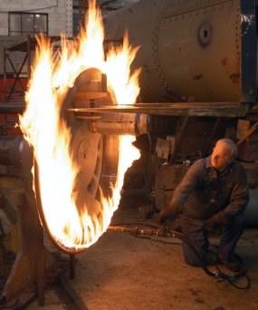 A new tire made of steel is enveloped in flame as it is heated to make it expand. Once it has expanded 80/1000 of an inch, it can be placed onto the wheel and the, as it cools, it shrinks to fit. A new tire made of steel is enveloped in flame as it is heated to make it expand. Once it has expanded 80/1000 of an inch, it can be placed onto the wheel and the, as it cools, it shrinks to fit.