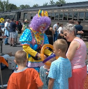 A clown celebrates with children at Carbondale, PA, the train which brought the children is in the background.