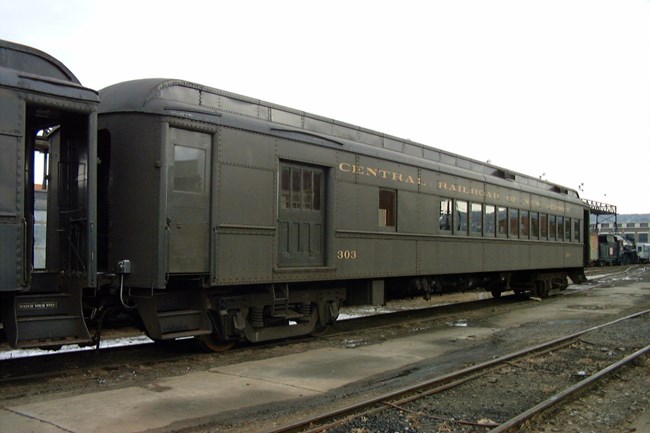 Central Railroad of New Jersey Combine Car #303, painted in dark green paint with railroad name and car ID in gold lettering