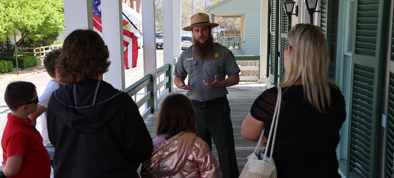 A park ranger speaking to a family group on a front porch