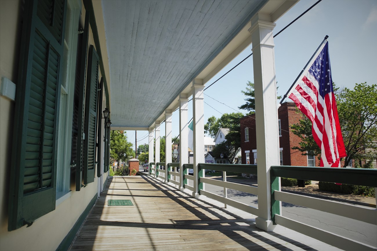 A view of a city street from a porch with an American flag and NPS flag