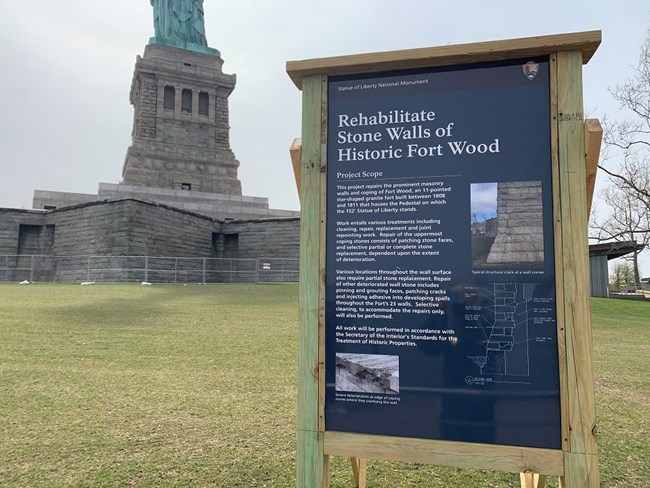 A photo of the sign explaining the Fort Wood rehab in front of the statue.