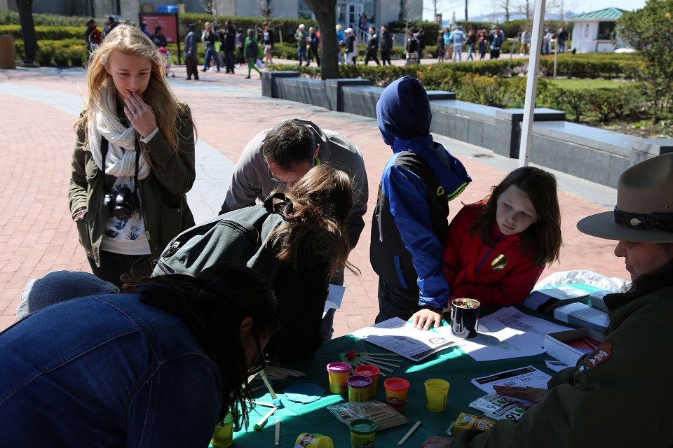 Seven people under a canopy finish a junior ranger activity sheet.