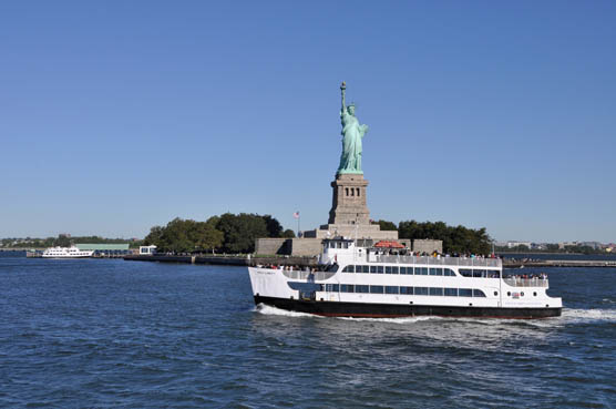 The ferry Miss Liberty passes in front of the Statue of Liberty.