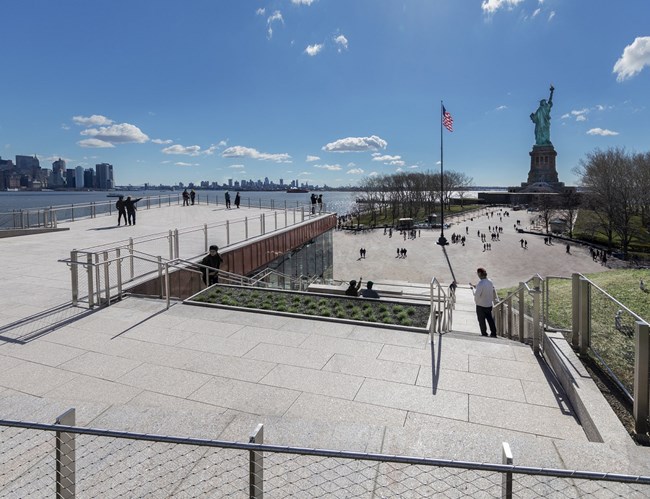 Open rooftop deck of the museum overlooking the flagpole plaza with the backside of the Statue of Liberty in view