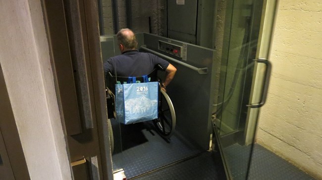 A visitor in a wheelchair is waiting to be lifted up to the top of the pedestal.