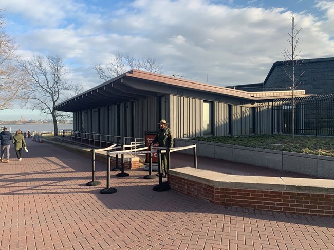 The secondary screening is a gray building which a park ranger is standing in front of.