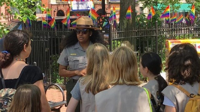 A park ranger is surrounded by park visitors.