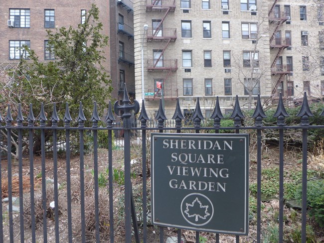 View of Sheridan Square Viewing Garden, which is NOT Christopher Park, with street sign saying Dave Van Ronk Avenue