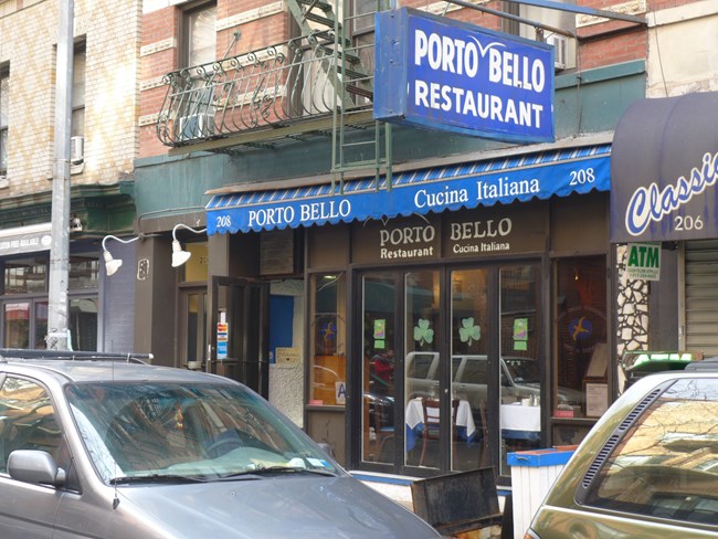 Entrance to the Porto Bello. A blue awning has the name of the restaurant, as does a blue sign.