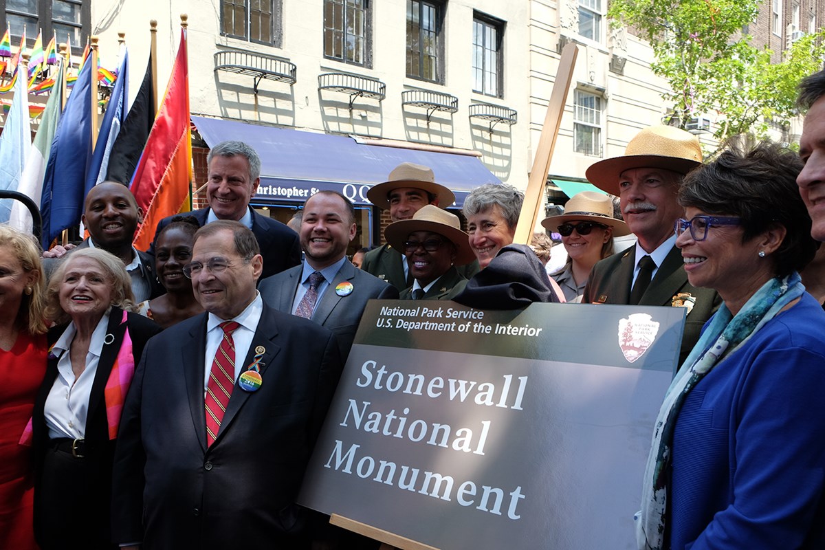 People gathered around a plaque that reads "Stonewall National Monument"