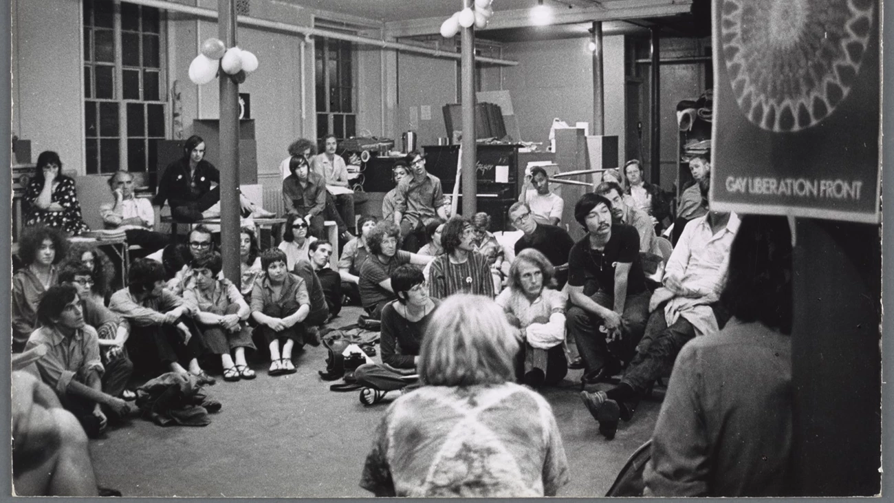 Gay Liberation Front Meeting at Washington Square Methodist Church, New York, 1970 Many people sitting in chairs and on the floor with a Gay Liberation Front (GLF) sign in the foreground