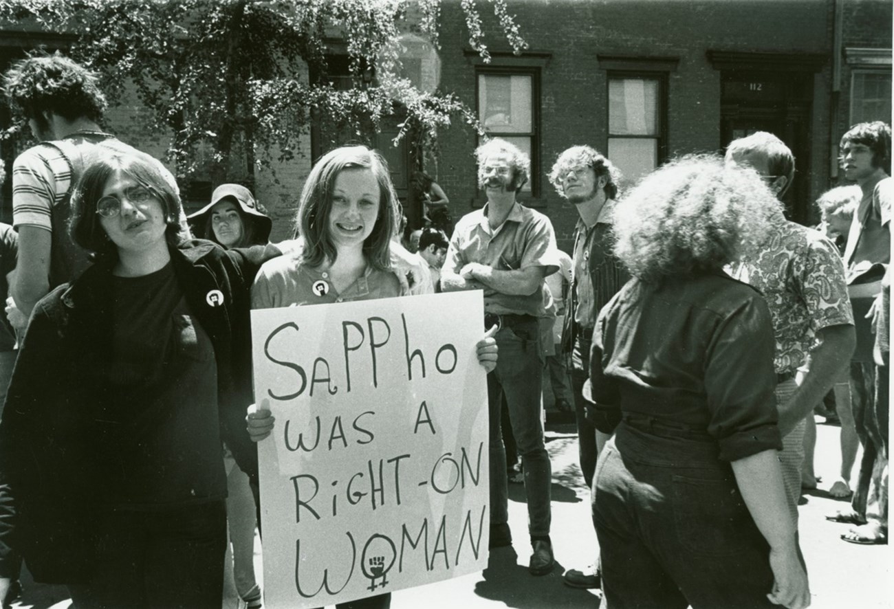 Gay Liberation Front (GFL) members Judy Cartisano and Stephanie Myers holding a sign that reads ‘Sappho was a right-on woman” at a gay pride demonstration