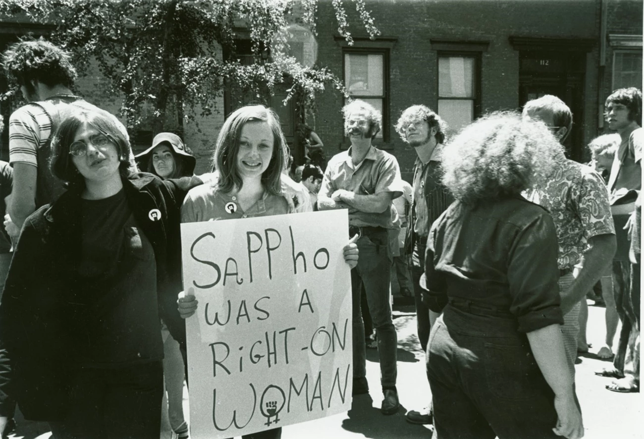 Gay Liberation Front Members Judy Cartisano and Stephanie Myers at a Gay Pride Demonstration, 1970 Gay Liberation Front (GFL) members Judy Cartisano and Stephanie Myers holding a sign that reads ‘Sappho was a right-on woman” at a gay pride demonstration