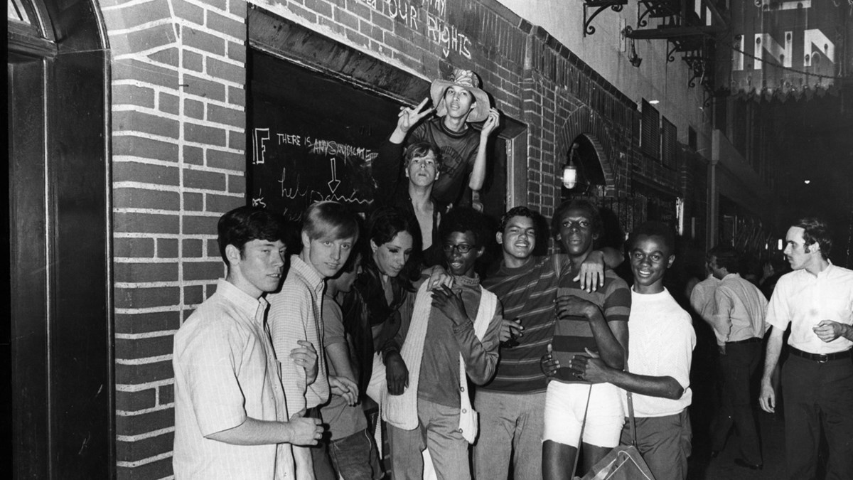 A group of young people celebrate outside the boarded-up Stonewall Inn