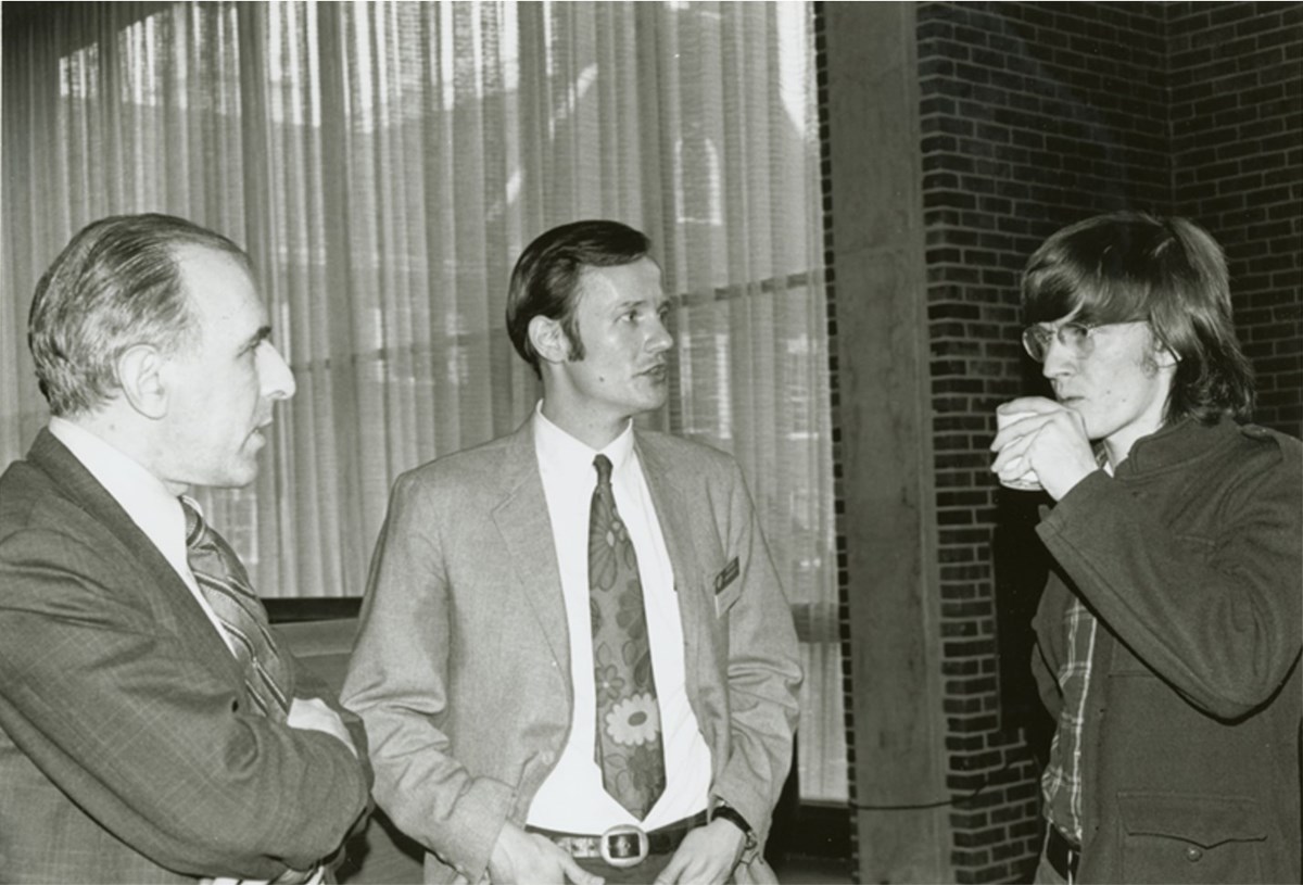 Frank Kameny, Randy Wicker, and Jim Owles standing and talking to each other at Gay Liberation Conference, 1971