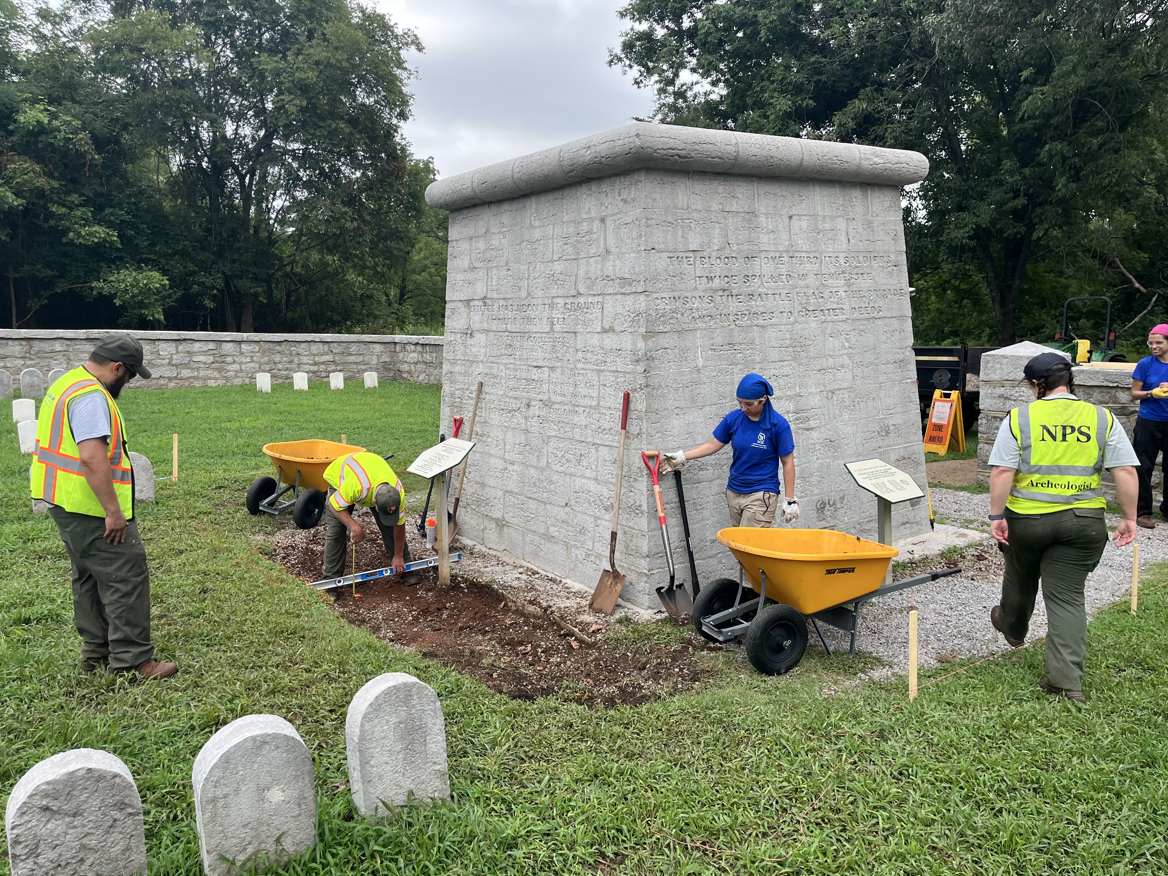 NPS employees and youth interns build a trail around a monument.