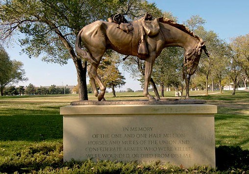 Statue of a horse with ribs showing on top of a pedestal with a plaque honoring horses and mules in the Civil War.