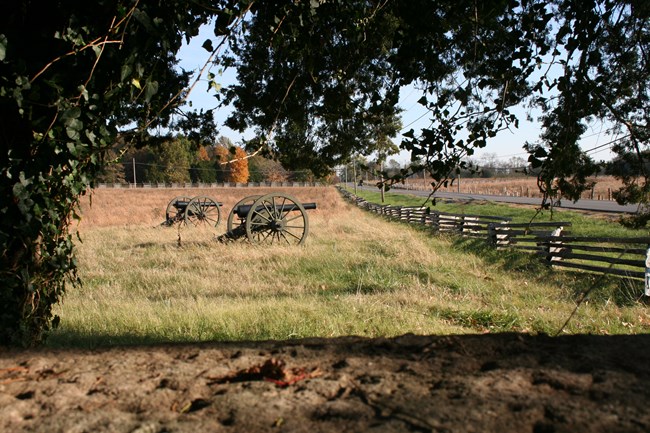 Two cannons overlook a highway and an open field