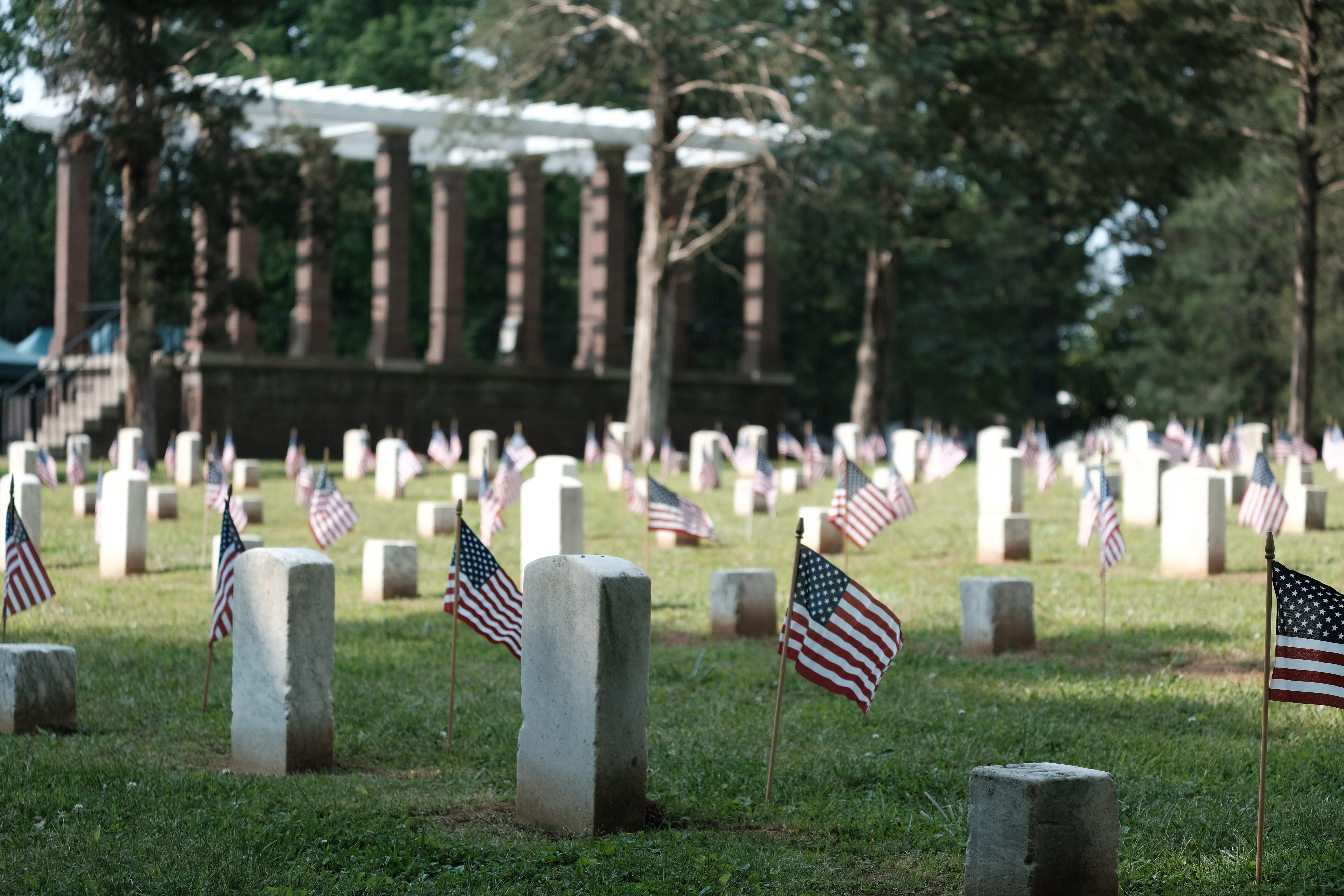 Erin Anfinson SRNB_4 American flags stand in front of headtsones arrayed in rows.