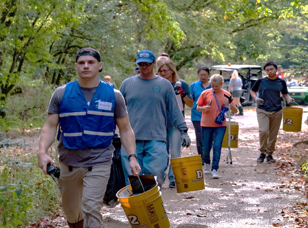 NPLD Volunteers Volunteers walk on trail carrying trash grabbers and buckets.