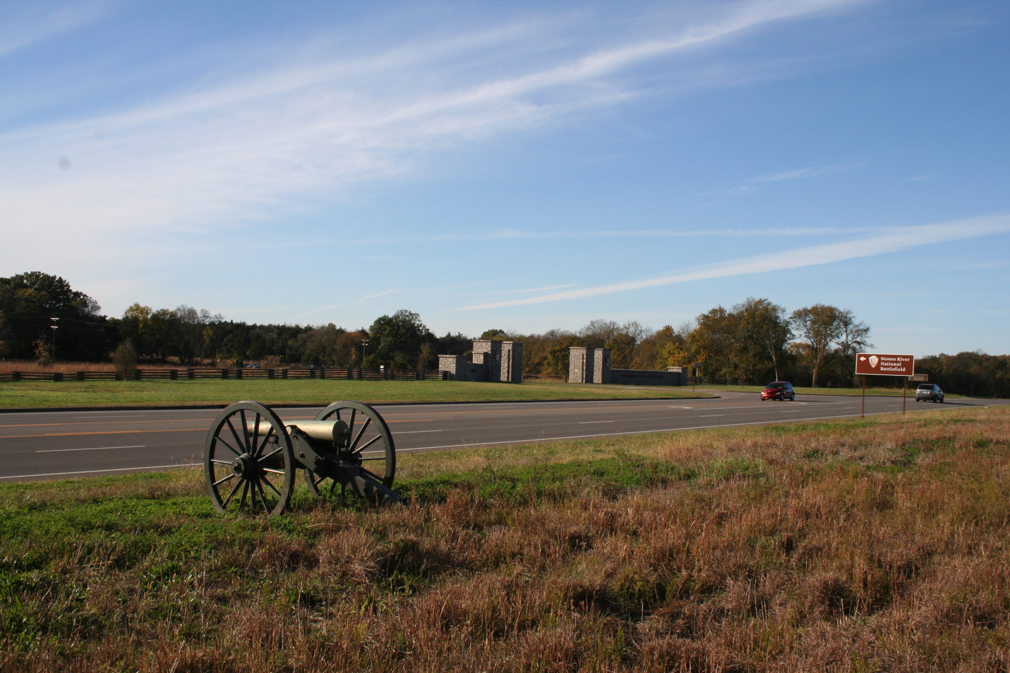 A cannon points across a road toward a stone gate.
