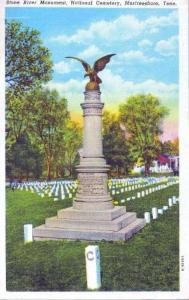 A brightly colored postcard shows the Regulars Monument in Stones River National Cemetery. It is a tall stone cylinder with a large bronze eagle on top of it.
