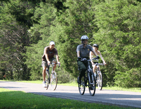 A park ranger leads two visitors on a bicycle tour.