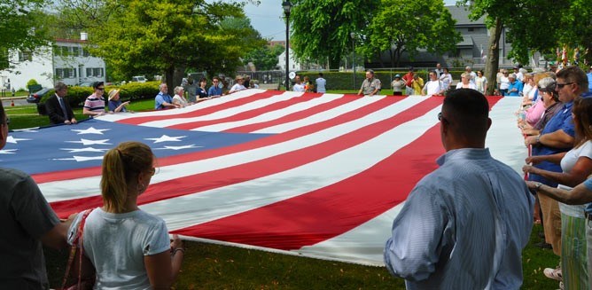 Photograph of a group of people holding a large American flag during an interpretive program.