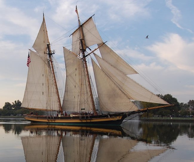A photograph of a schooner will full sails underway.