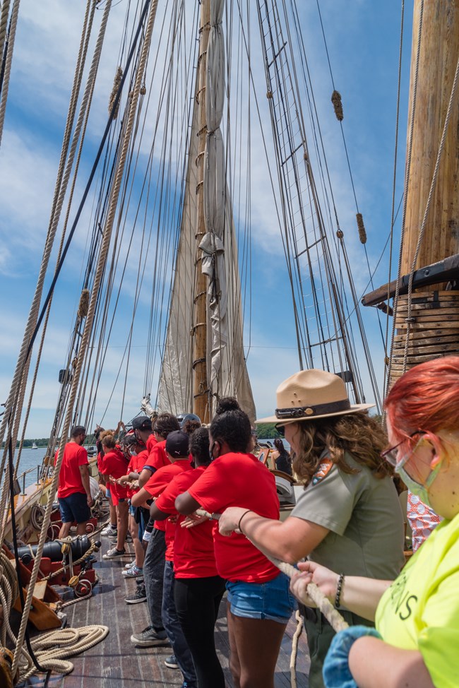 A Park Ranger helps participants pull ropes on the Pride of Baltimore II.