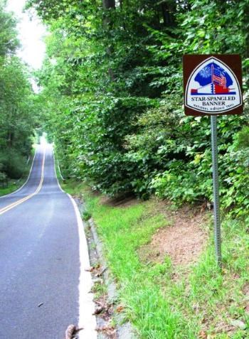 A Star-Spangled Banner Trail Marker along a two-lane road.