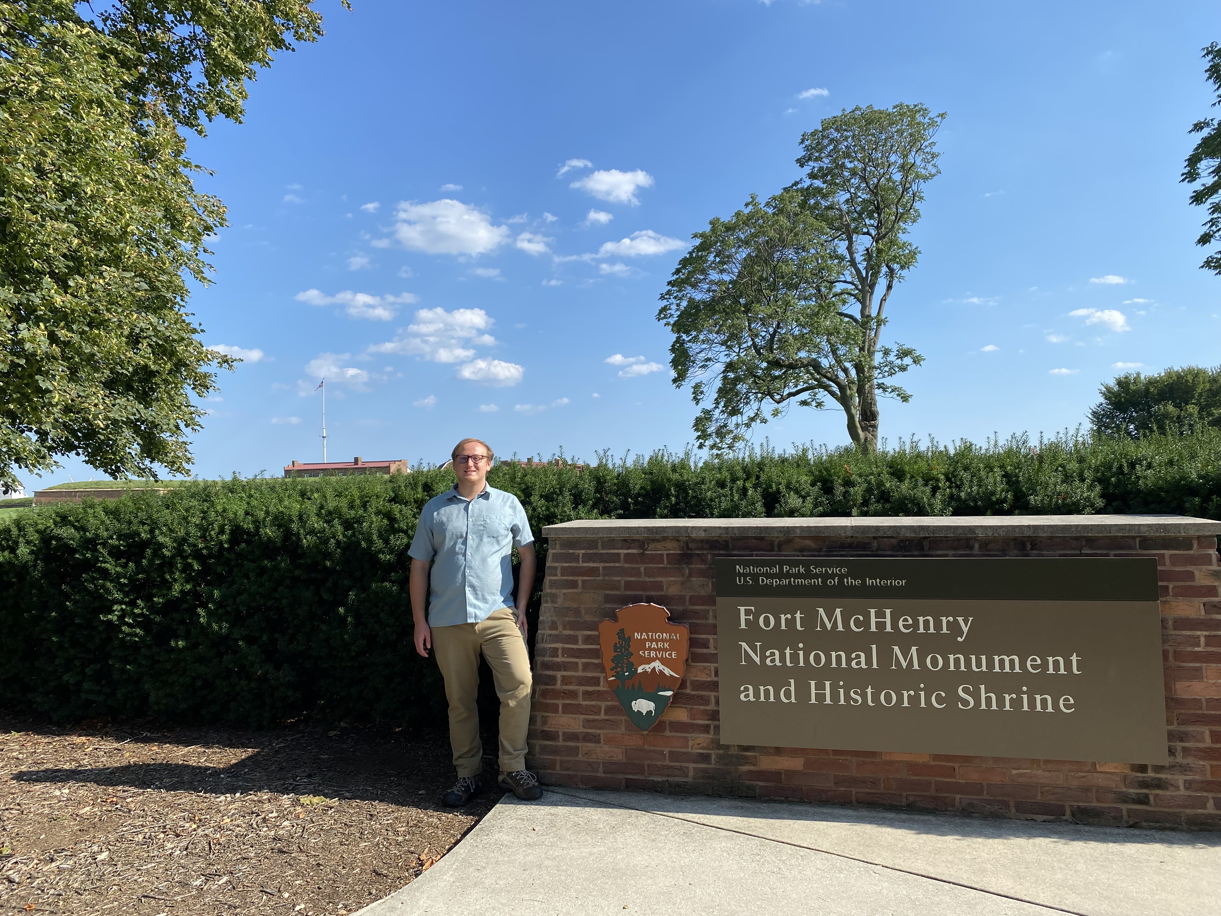 A man standing next to a park sign.