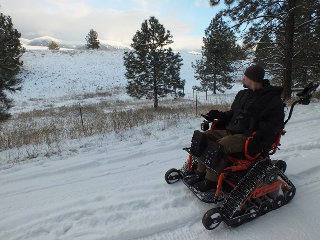 Man gazing across a snowy mountain landscape on his Action Tract Off-road Mobility Device