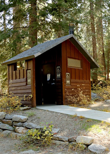 Wheel-chair accessible vault toilet Wooden building with accessible restroom signs