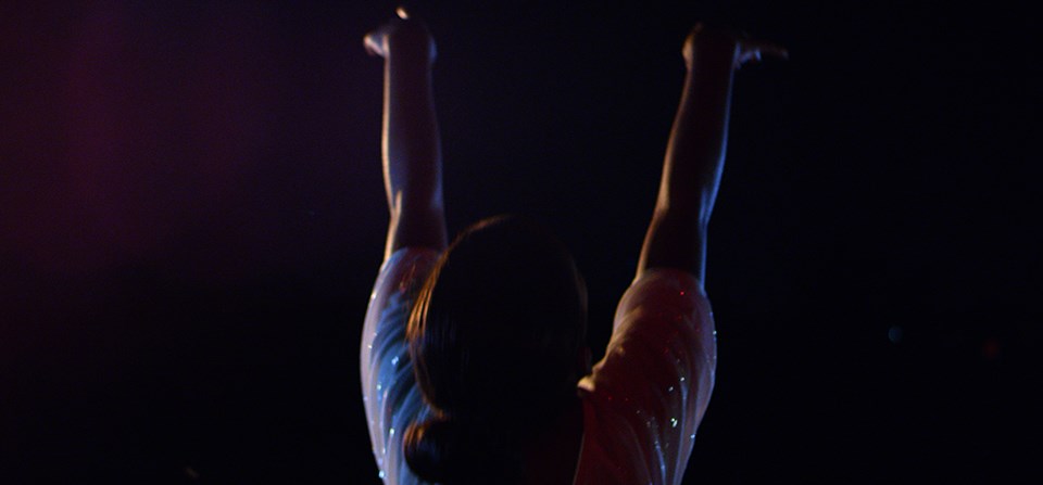 against a night sky a young African American ballerina raises her arms in dance