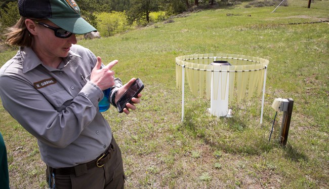 Person pointing to a rain gage