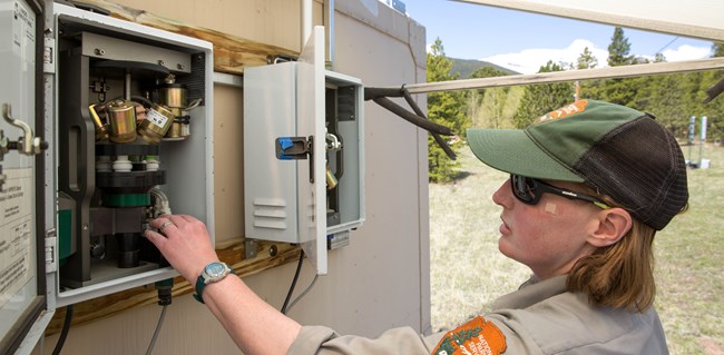 Change IMPROVE filter packs An NPS employee looking at outdoor air monitoring equipment