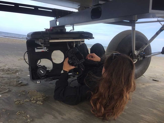 A scientist fits a camera in the belly plate of a plane.