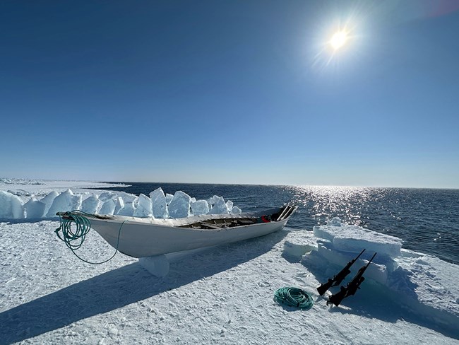 The Arctic coast covered in ice and snow. A native fishing boat on the ice.