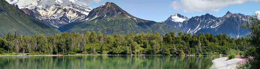 Sun is shining, the aqua green water is calm and the mountains of Lake Clark pristine.