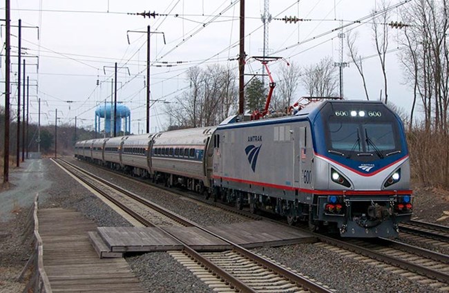 The Northeast Corridor train rides on track with electric lines overhead. The Northeast Corridor train rides on track with electric lines overhead.