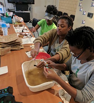 Archeologists wash artifacts in plastic tubs. NPS photo.