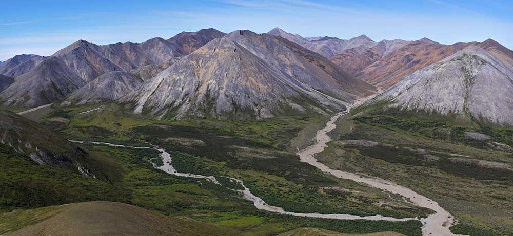 Colorful mineral mountains of the Brooks Range over vast rivers and tundra.
