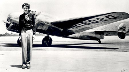Earhart and her plane A tall woman stands in front of a plane