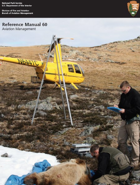RM60 Cover A yellow helicopter on a slope with two men standing over a prone bear